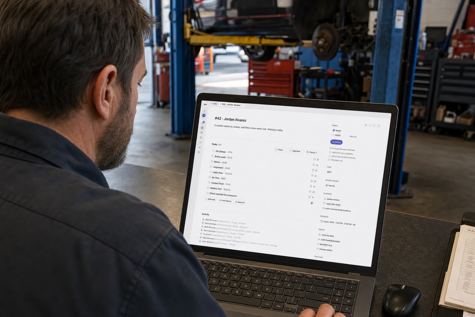 Service advisor at a shop desk reviewing repair order RO-42 with line items and an $812 total